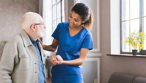 A nurse is helping an older man to put on his medical gloves.