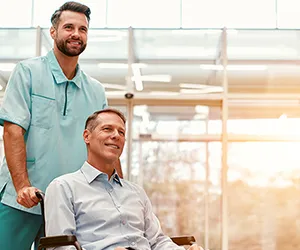 A man in a wheelchair with another man standing next to him.