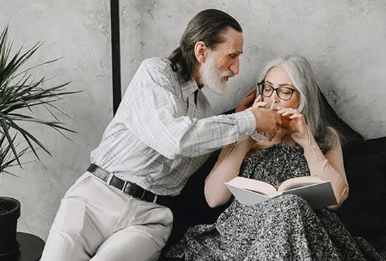 A man and woman sitting on the ground with one hand touching another 's ear.