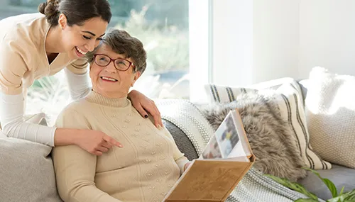 A woman and an elderly person looking at a laptop.