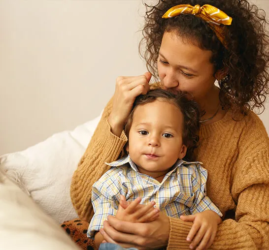 A woman is holding a child and touching her hair.