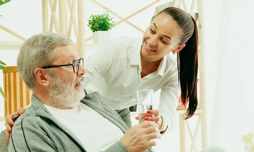 A woman is holding a glass of water and talking to an older man.