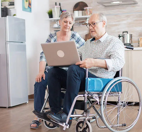 A man and woman sitting in front of a laptop.