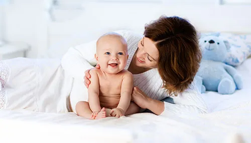 A woman is holding a baby and smiling.