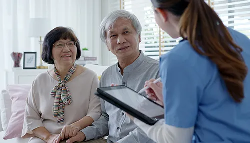 A woman is talking to two older people