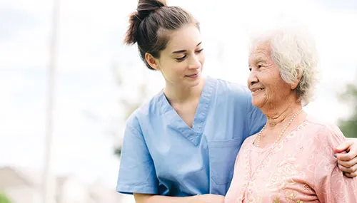 A nurse and an elderly woman smiling for the camera.