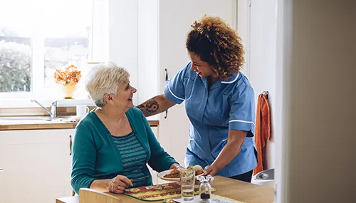 A nurse is helping an elderly woman to eat.