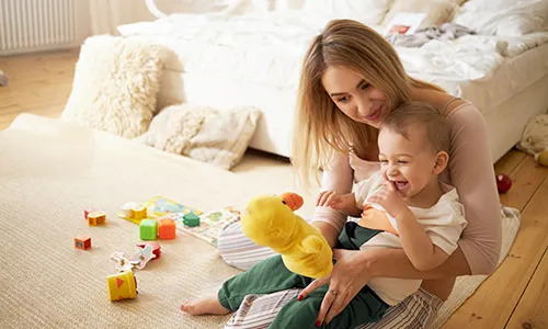 A woman and child playing with toys on the floor.