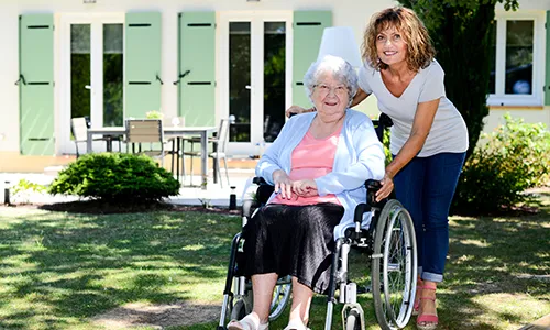 A woman pushing an elderly lady in a wheelchair.