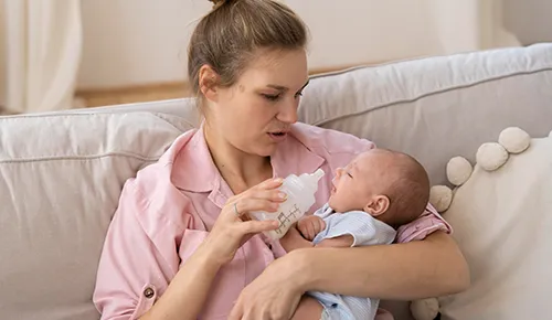 A woman holding a baby and feeding it