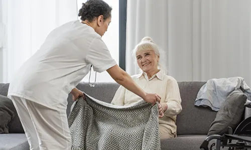 A person is holding a blanket over an older woman.