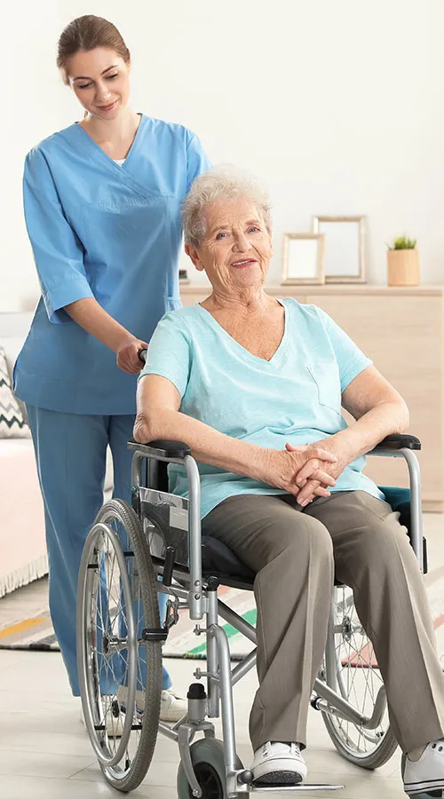 A woman in blue shirt and brown pants standing next to an older person.