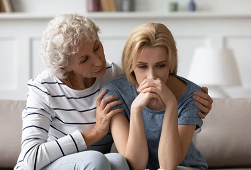 A woman sitting next to an older woman on the couch.