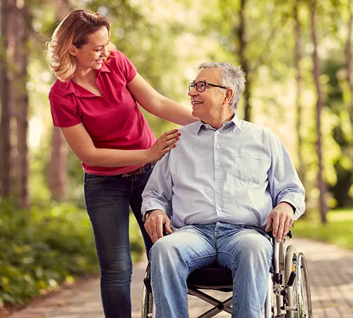 A woman is helping an old man in a wheelchair.