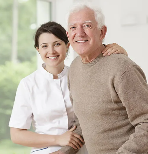 A nurse and an old man smiling for the camera.