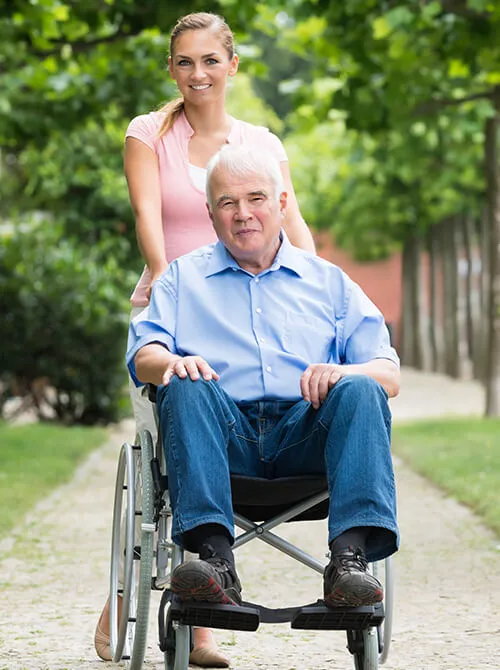 A man in a wheelchair with a woman behind him.