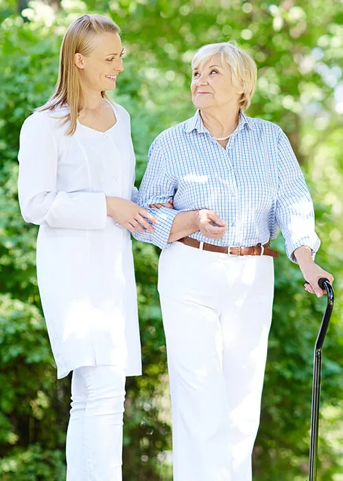 Two women standing next to each other in a park.