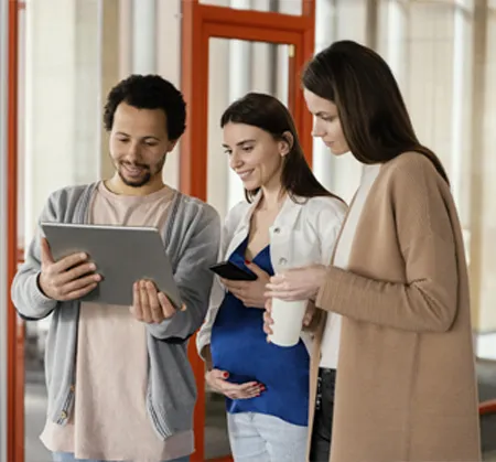 Three people standing around looking at a tablet.